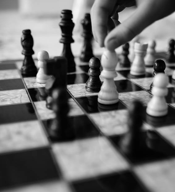 Fekete-fehér fotó egy sakktábláról, ahol egy stratégiai lépés történik, szimbolizálva a profi SEO versenytárselemzést és a konkurencia megelőzését.