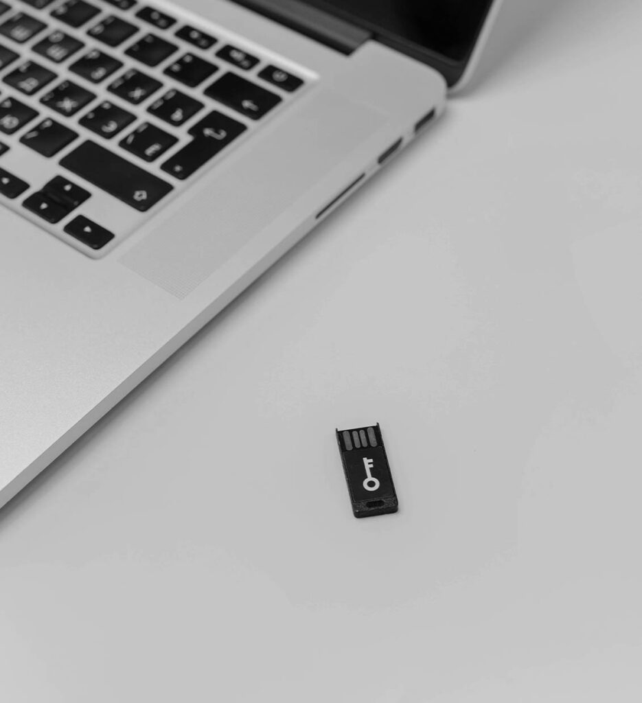 Biztonsági USB kulcs egy laptop mellett, ami az adatvesztés elleni heti automatikus biztonsági mentést és a weboldal hiba esetén történő gyors visszaállítását szimbolizálja.